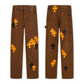 Brown carpenter pants with orange and black cross patches
